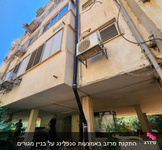בניין עם מזגנים וצינורות חיצוניים, אנשים עובדים למטה